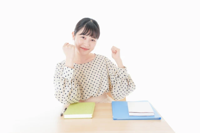 机の前でガッツポーズする女性