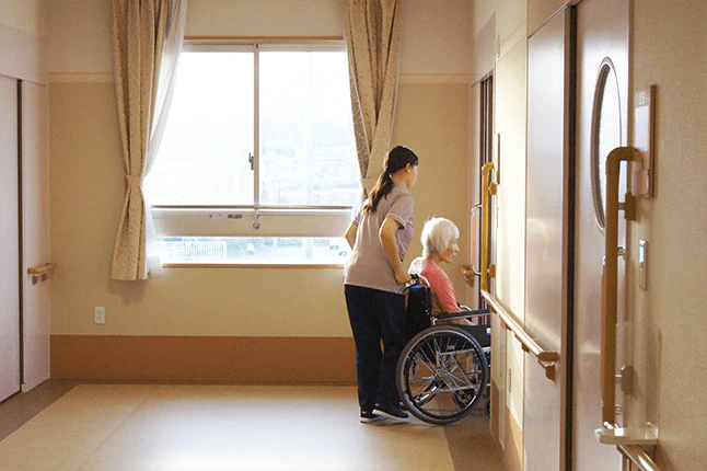 車いすに座る施設利用者と車いすを押す介護職員