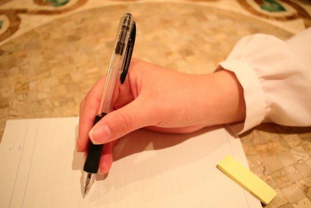 ノートとペンを握る人間の手