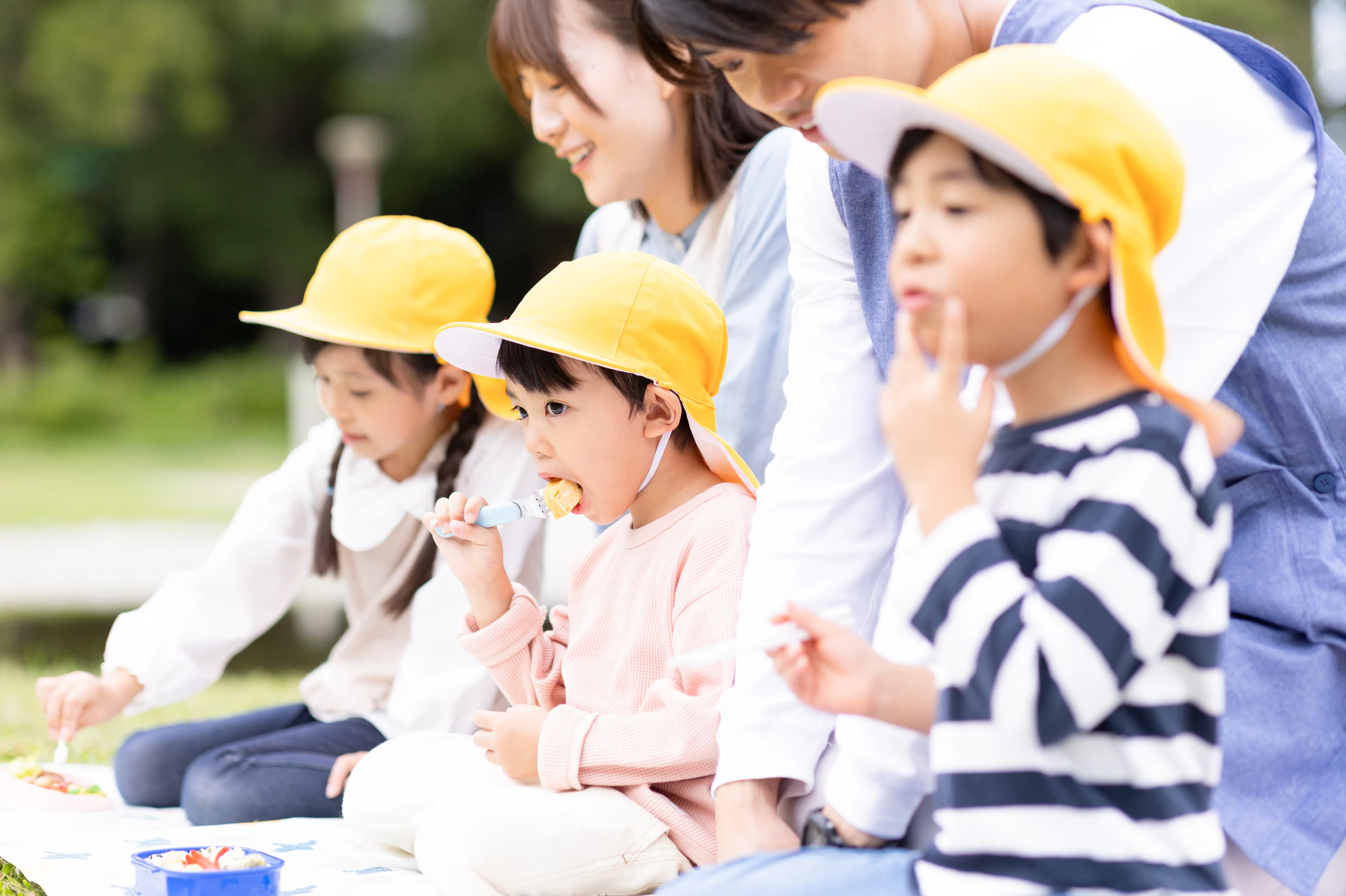遠足でおにぎりを食べる男の子
