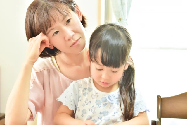 女の子を抱っこしながら考え事をする女性