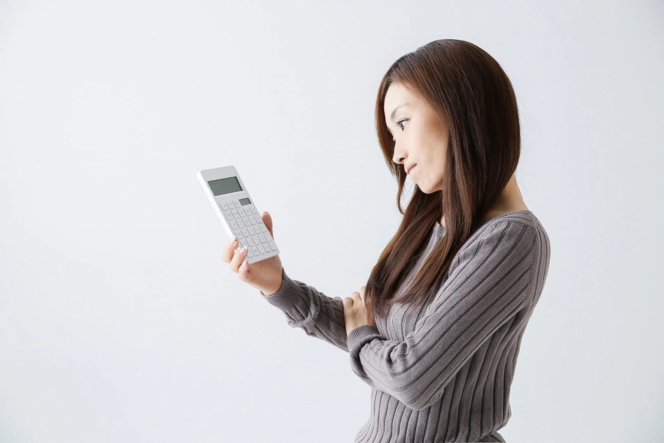 電卓をみて考えている女性