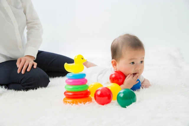 カラフルなおもちゃで遊ぶ赤子と見守る母親