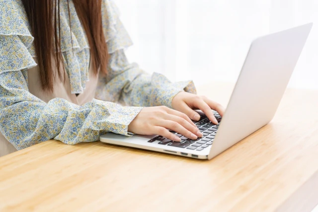 ノートパソコンのキーボードを打ち込む女性