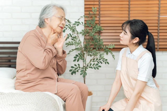 ベットで話しをする女性とスタッフ