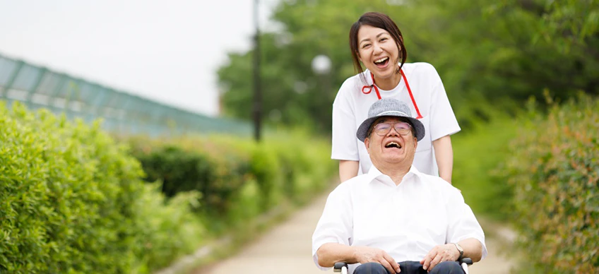 理学療法士が車いすに乗るおじいさんと笑顔で会話
