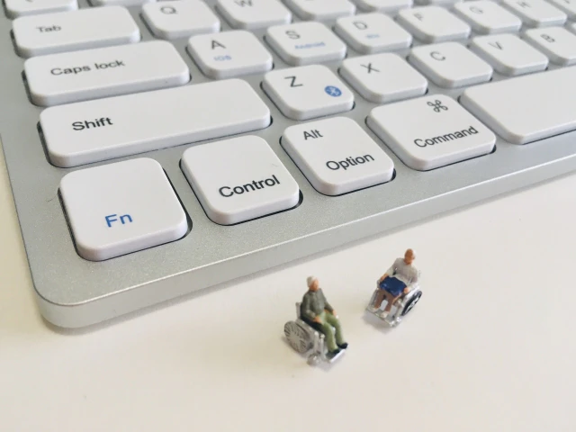 パソコンのキーボードと車いすの2人