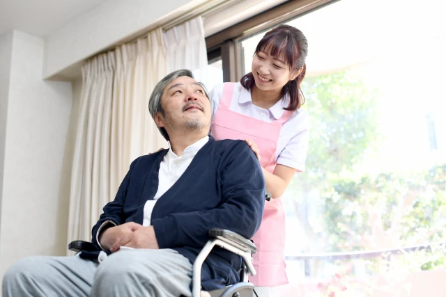 車いすの男性と笑いかけるスタッフさん