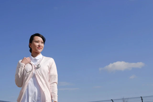 青空の下屋上に立っている看護師