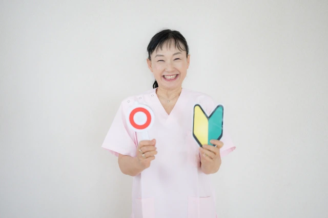 丸の札と初心者マークを持つ笑顔の女性