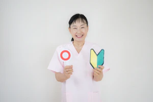 丸の札と初心者マークを持つ笑顔の女性