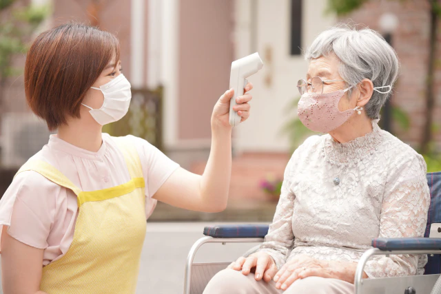 体温を測る高齢者とスタッフ