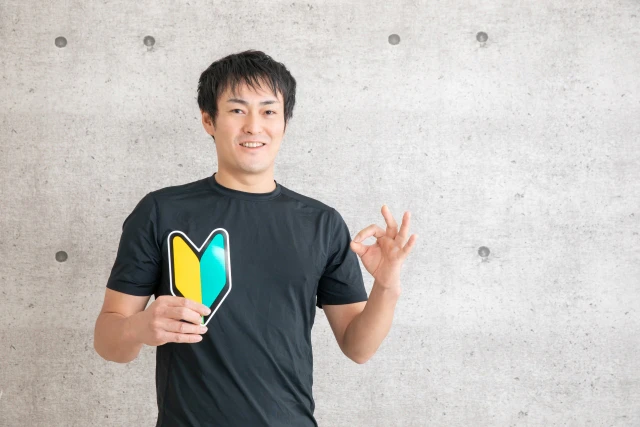 初心者マークを持ちOKサインを出す男性