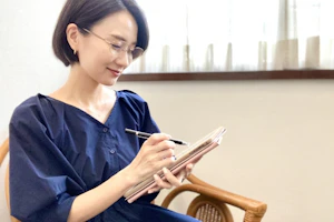 メモを取りながら微笑むメガネの女性