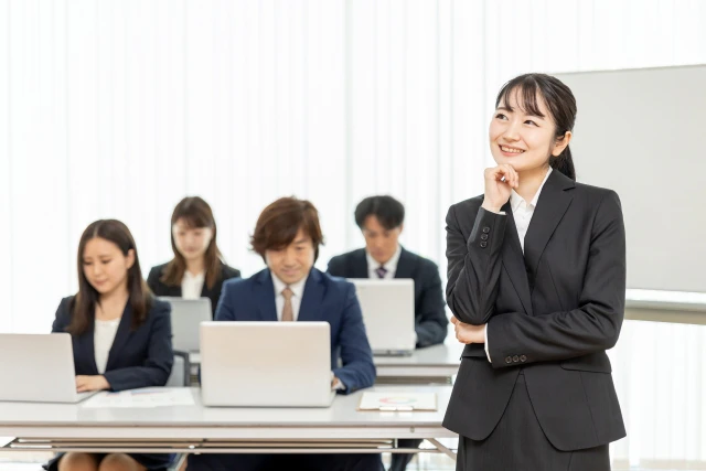 考える女性とノートパソコンに向かい合う男女