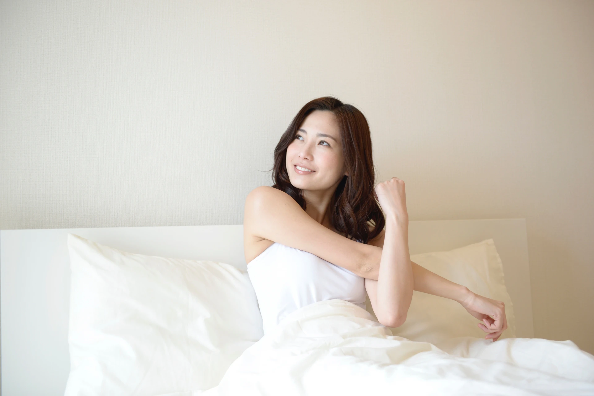 女性がベッドから朝日見る