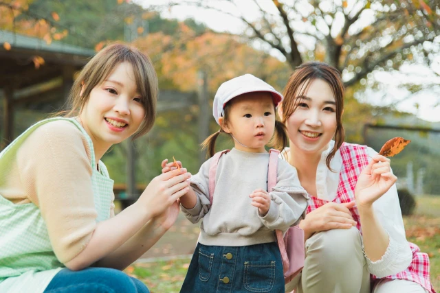 2人の保育士が子どもを囲んでいる戸外保育