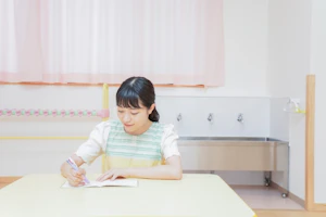 ノートに記入する保育士