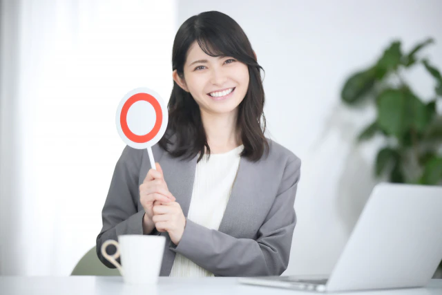 〇の書かれた棒を持つ笑顔の女性