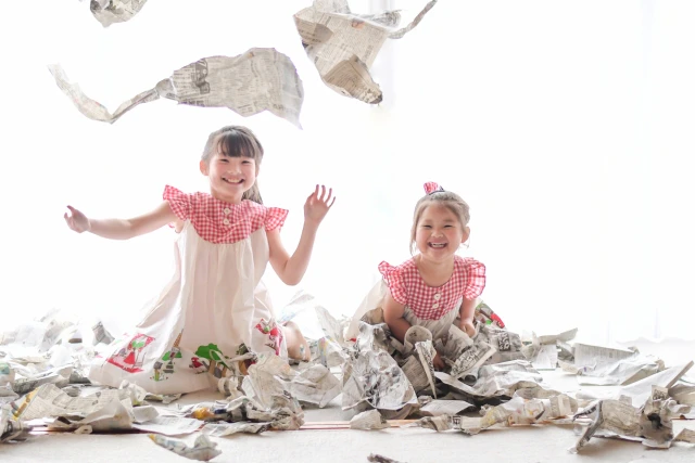 新聞紙遊びをして笑顔の2人の女児