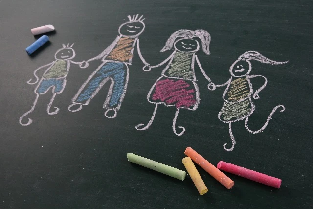 黒板にチョークで家族の絵を描いている