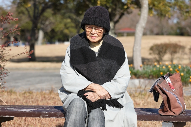 公園のベンチに座っている高齢女性