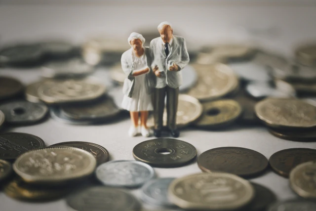 たくさんの硬貨に囲まれるミニチュアの老夫婦