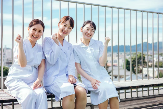 屋上でガッツポーズする３人の女性看護師