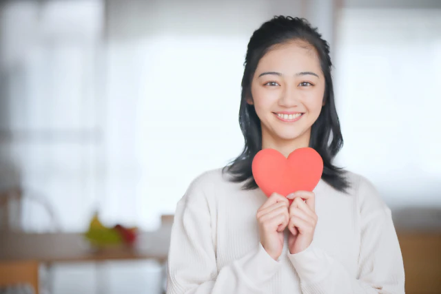 ハートマークを持った笑顔の女性