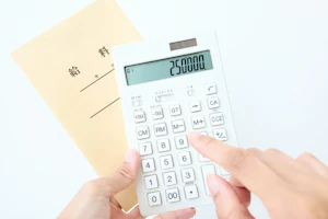 給料袋を持ち電卓を使って手取り金額を計算する