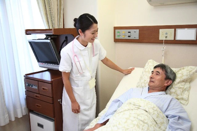 ベッドで横になる患者さんに話しかけている看護師