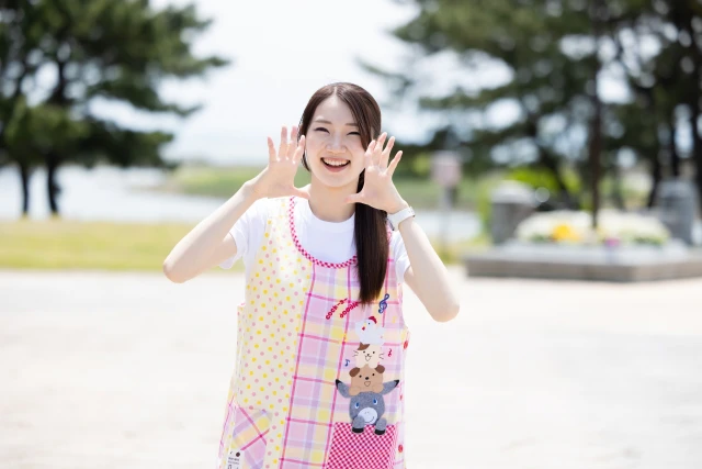 口の横で両手を広げる保育士さん