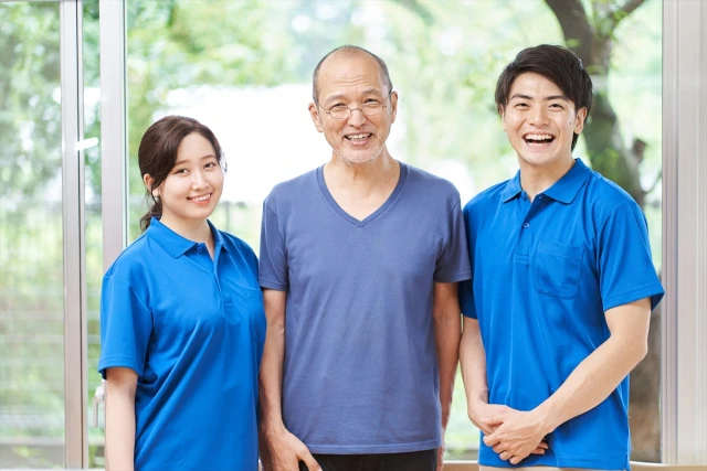 笑いあう高齢男性と男女のスタッフ