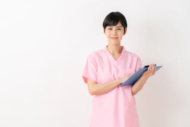 ファイルを持って正面を見ている看護師