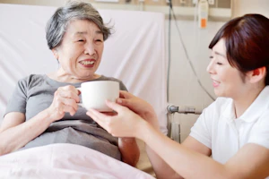 ベットの高齢者とスタッフ