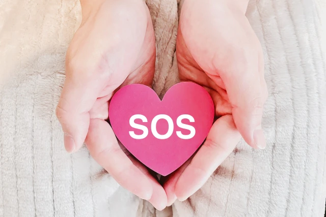 「SOS」と書かれたブロックを包み込む手