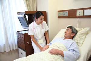 ベッドに寝ている患者さんと話している看護師