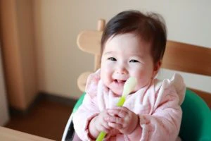 スプーンを持つ笑顔の赤ちゃん