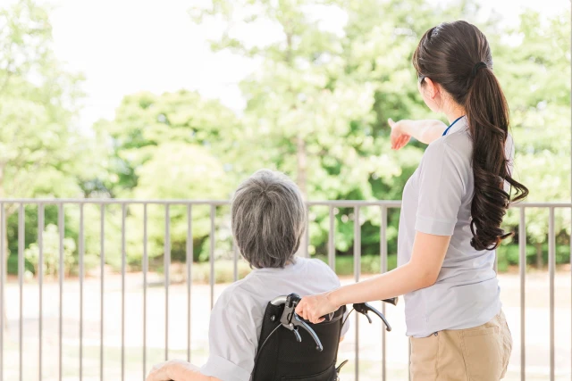 外を見る車椅子の女性とスタッフ