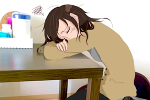 机に突っ伏して考え込んでいる看護師