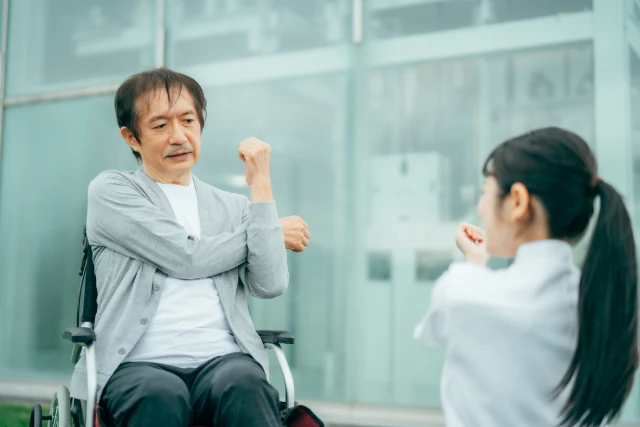 スタッフと一緒に体操をする車椅子の男性
