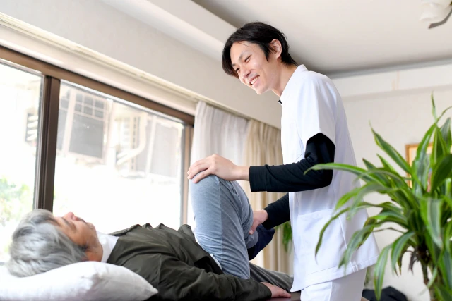 男性の脚を持ち上げるスタッフ