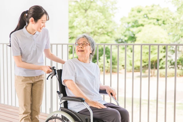 笑い合う車いすの女性と介助する女性