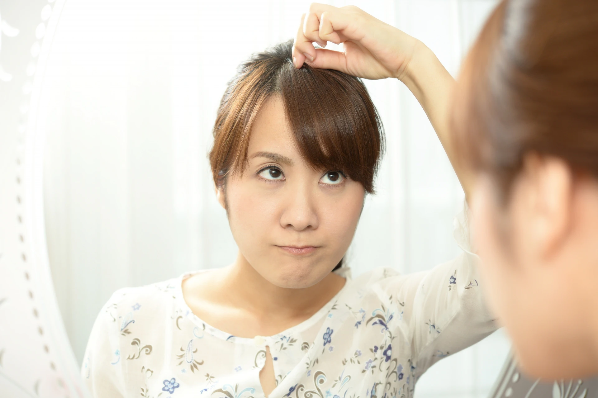 鏡の前で前髪を整える女性