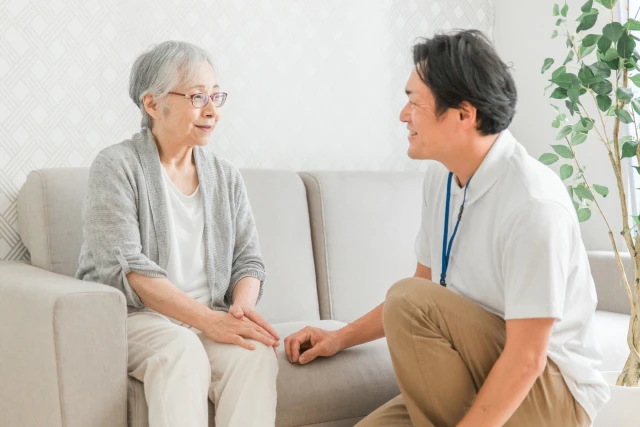 ソファーに座る高齢女性と男性スタッフ