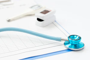 カルテの上に置かれた聴診器、血圧計、体温計