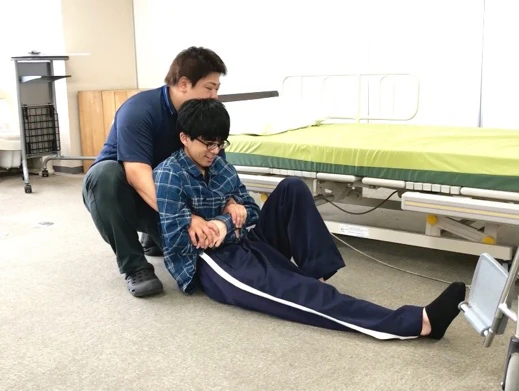 両脇から手を回し、麻痺のない左手をしっかりと持つ