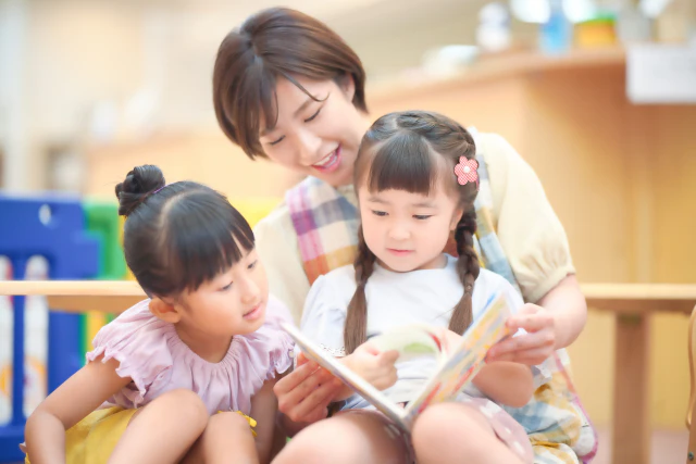 子ども2人を膝に乗せる保育士