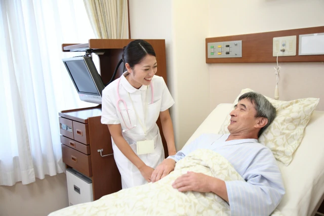 ベッドで寝ている患者さんと話す看護師