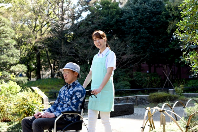 散歩中の車椅子の男性とスタッフ